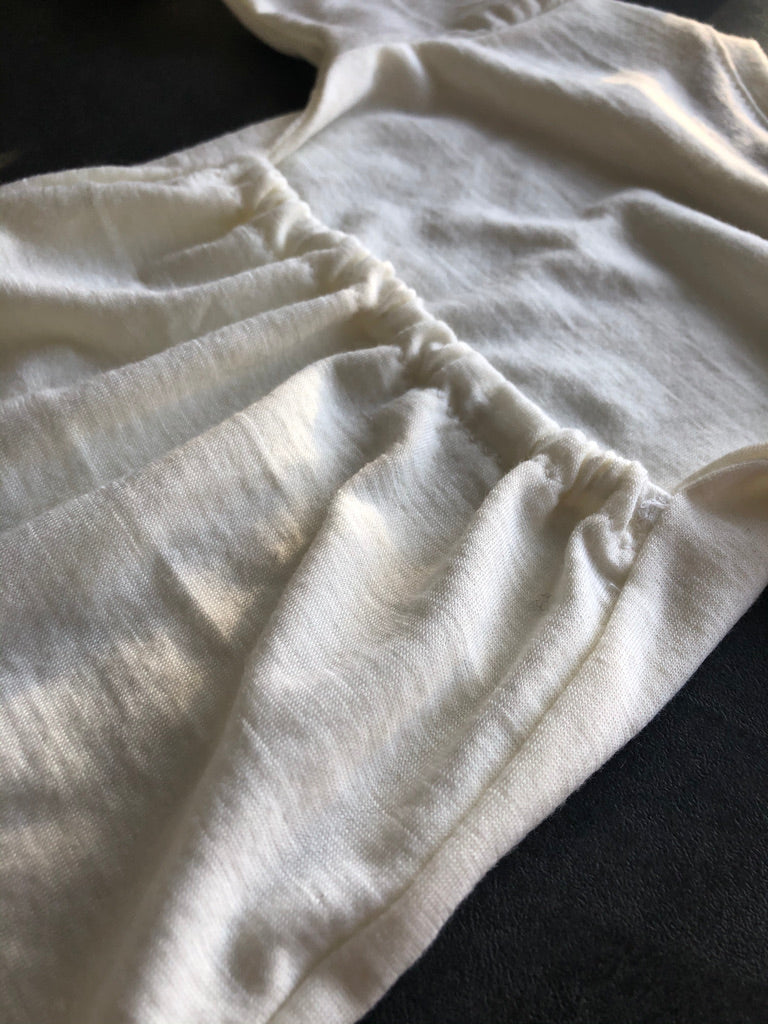 Close up of the elasticated back of the merino sleep suit in Ivory