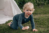 Baby crawls across the grass wearing merino toddler pyjamas